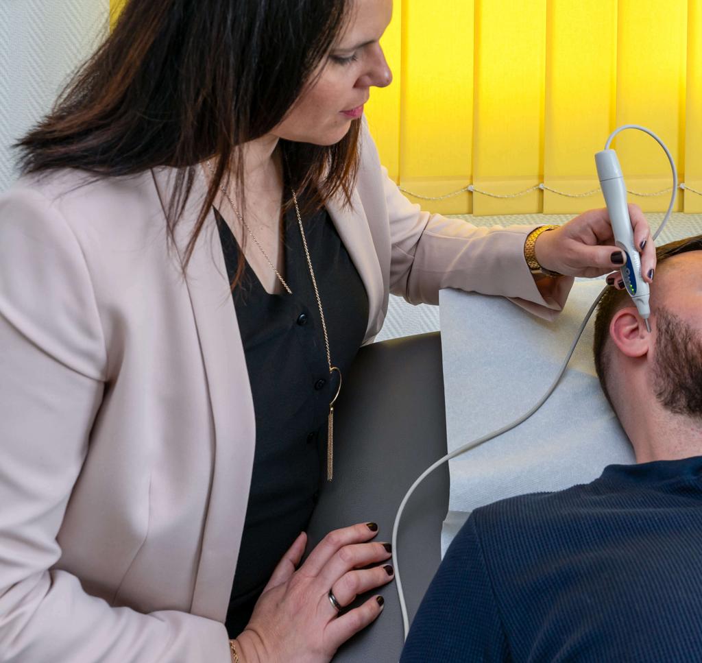 Praticienne réalisant une séance d'auriculothérapie laser